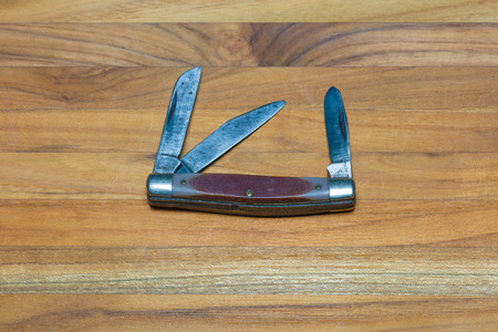 A pocket knife with multiple blades against a wood backgroundの写真素材