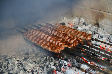 Meat skewers grilling over hot barbecue coalsの写真素材