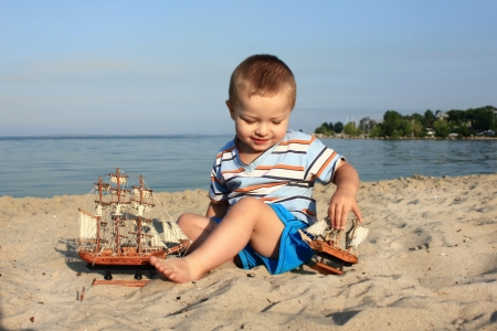 a little boy on the beach with a ship  の写真素材