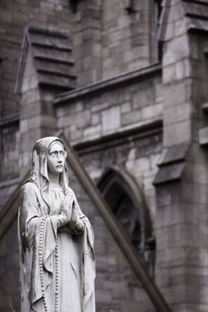 A sculpture of a praying saint on the courtyard of a church in Dublin.の写真素材