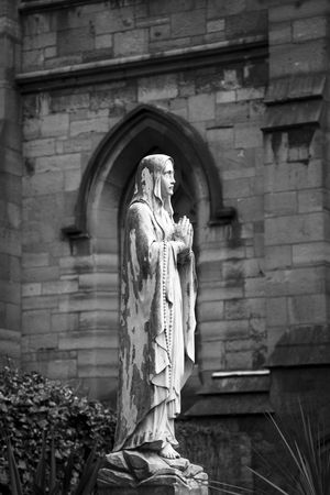 A sculpture of a praying saint on the courtyard of a church in Dublin.の写真素材