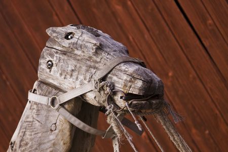A worn wooden horse on a red painted wall background.の写真素材