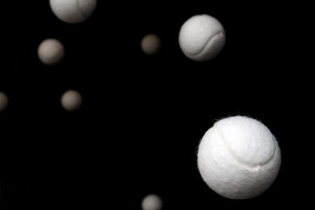 White tennis balls against a black background.の写真素材