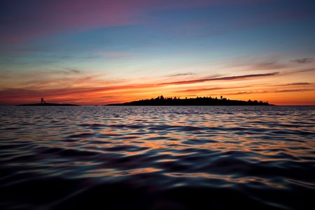 An island outlined in the colourful light from the sunset.の写真素材
