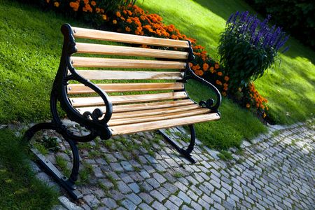 A bench in the park, next to floral arrangements.の写真素材