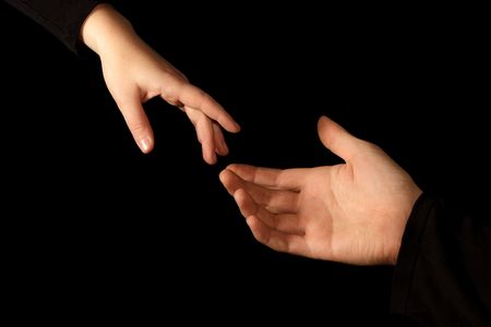 Two hands isolated on black background, one female, one man. Hands almost touching.の写真素材