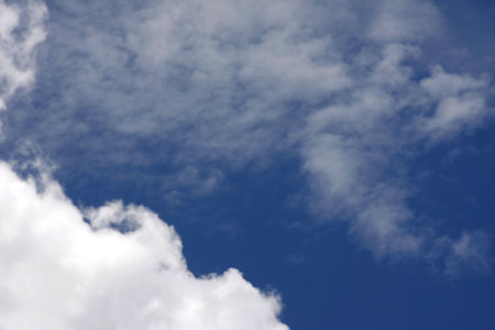 Thick fluffy clouds on left with thinner clouds on right.
