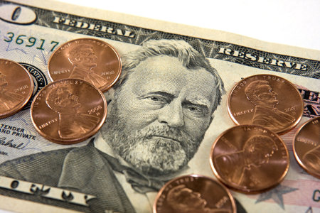 Stack of pennies on top on a fifty dollar bill against a white background.