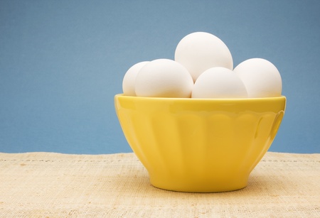 Bowl of uncooked white eggs in a yellow bowl.の写真素材