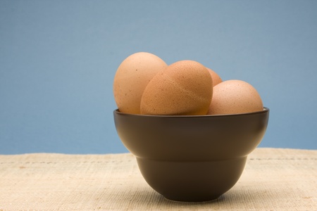 Bowl of uncooked brown eggs in a brown bowl.の写真素材
