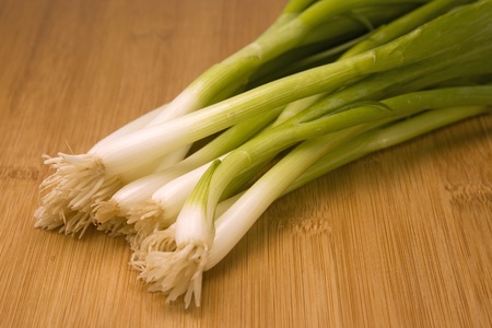 Bunch of fresh green onions laying on a wood chopping block.の写真素材