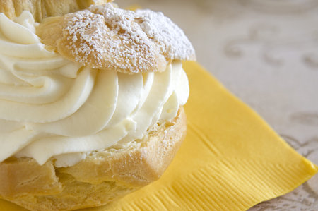 Close up of a creme puff pastry dessert on a yellow napkin.