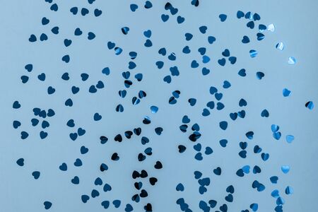Blue hearts glitter on soft blue backdrop. Decorative Christmas and New Year party background. Festive template. Greeting card with copy space. Colorful tinsel. Glitter textureの写真素材