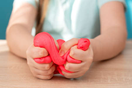 Child crushes and crumples pink slime in her hand.の写真素材