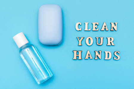 Hand cleaning gel and soap with words Clean your hands made by wooden letters on pastel blue background. Coronavirus prevention sanitizer gel for hand and soap. Minimal concept. Flat layの写真素材