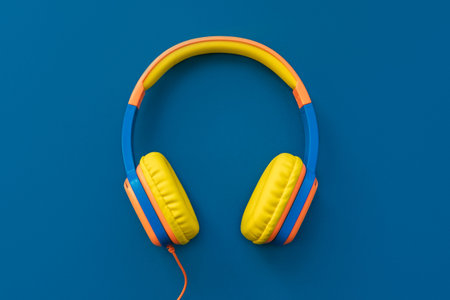 Multi-colored headphones on blue background. Minimalistic fashion music concept. Trendy color of the...