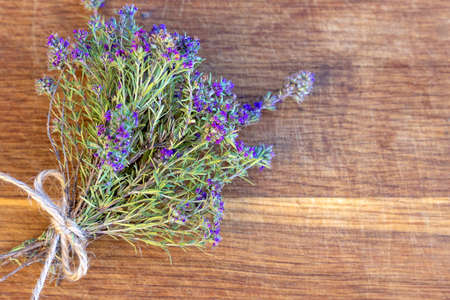 A bunch of fresh thyme lies on an old wooden background. Top view, flat lay. Fresh herb. Selective focus, copy spaceの写真素材