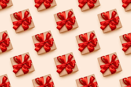 Seamless pattern of gift box in craft paper and with decorative red ribbon on beige background. Top...
