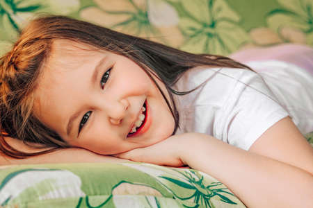 Portrait of a little beautiful smiling girl. Little cute girl having fun and rest outside in summer.の写真素材