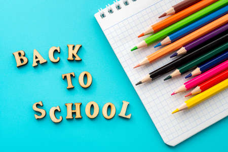 Wooden letters, notepad and color pencils on turquoise background. From above inscription Back to school and bright colorful pencils on turquoise surface. Concept of back to school and education.の写真素材