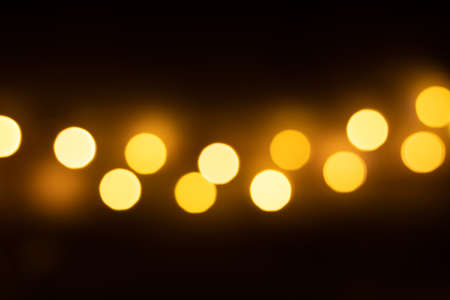 Abstract golden glitter light bokeh defocused isolated on the black background for overlay design. Gold confetti scatter on black background. Holiday disco pattern for backdrop.の写真素材