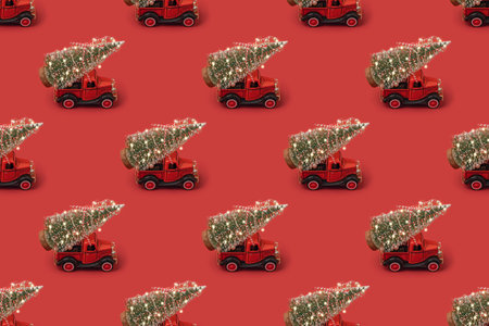 Samless pattern of red small retro toy truck with sparkling Christmas tree lights on truck body on...