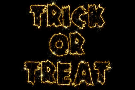 Sparkling burning text Trick or Treat isolated on black background. Beautiful overlay template object for design holiday greeting card, billboard and web banner.の写真素材