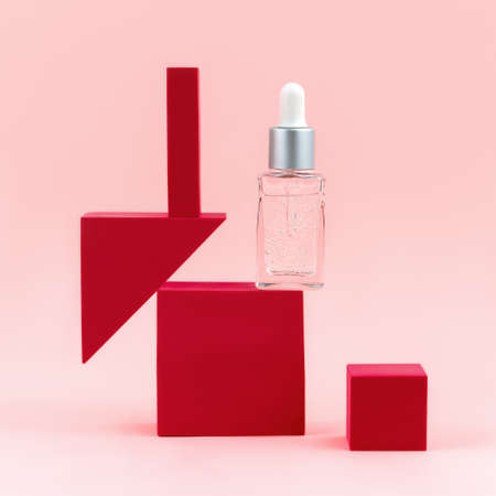 Cosmetic serum bottle on pink background. Beauty wellness natural concept. Pedestal product display creative concept. Geometric shape podiums clipart with copy space. Front view.の写真素材