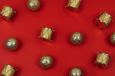 Christmas decoration pattern, with christmas golden balls and golden toy drums against red background. Flat lay, top view. Christmas minimal pattern background.の写真素材