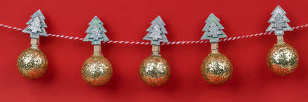 Christmas composition. Banner of christmas garland with hanging by wooden pins golden shiny balls against red background. Christmas, winter, new year concept. Front viewの写真素材