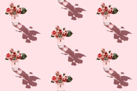 Seamless pattern of a glass with water and pink flower mini Rose called Mimi Eden with drops of water against bright pink background. Minimal flowers concept in hard light with shadows. Front view.の写真素材