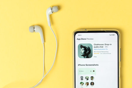 Severodvinsk, Russia - 17 February 2021: Clubhouse drop-in audio app view on the smartphone and earphones on trendy yellow background. Trend of 2021. Top view, flat lay.のeditorial素材