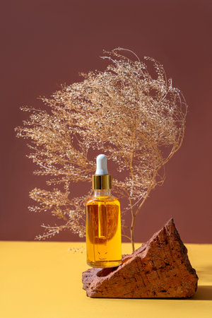 Cosmetic glass bottle with dropper for essential oils, creams and serum stand on stone over brown...
