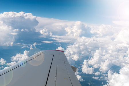 View from airplane window with blue sky and white clouds. Clouds and sky as seen through window of...