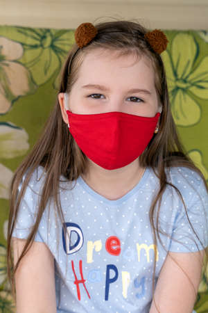 Close up photo of pretty happy and smiling child looking into camera wear red breathing reusable mask. Coronavirus Covid-19 and Air pollution concept.の写真素材