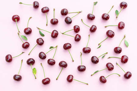 Cherry pattern. Flat lay of cherries and leaves on pastel pink background. Food background. Cherries flat design. Top view, flat lay.の写真素材