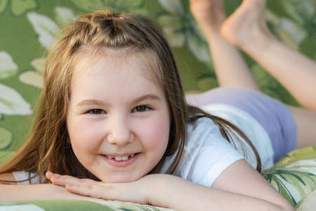 Portrait of a little beautiful smiling girl. Little cute girl having fun and rest outside in summer.の写真素材