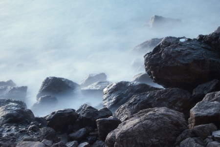 stones in the sea, water looks like fog due to long exposureの写真素材