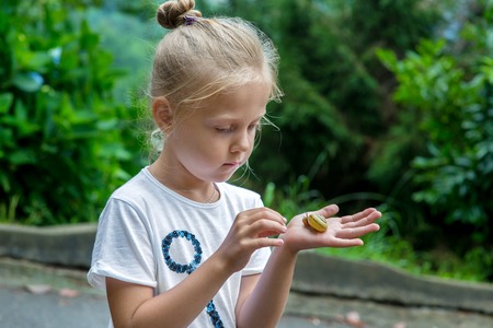 little young beautiful girl holding small snail in handの写真素材