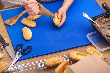 Eclair preparing on kitchen wooden table with kitchenware, top viewの写真素材