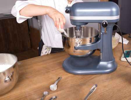 Cream mixing on wooden kitchen table with kitchenwareの写真素材