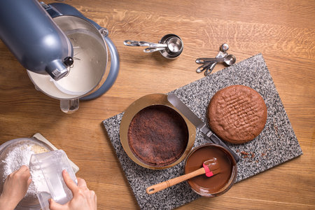 chocolate cake baking ingredients on wooden kitchen table with kitchenware, top view