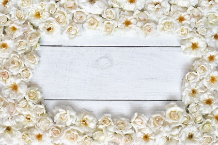 Frame of white rose flowers on white wooden table, top viewの写真素材