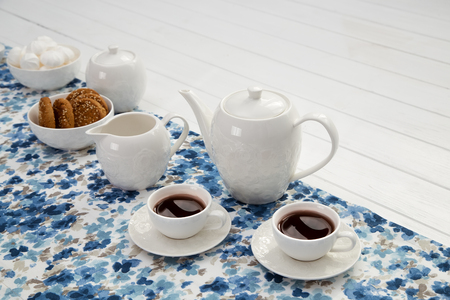 cups of coffee with milk, cream and biscuits on wooden white tableの写真素材