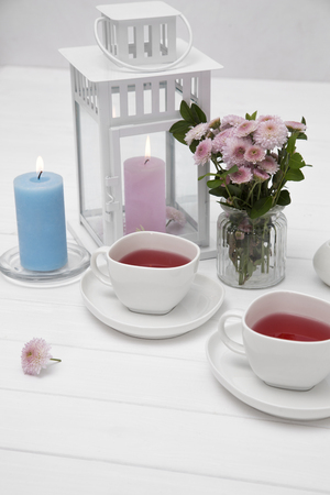 cups of fruit tea on wooden white table decorated with flowersの写真素材