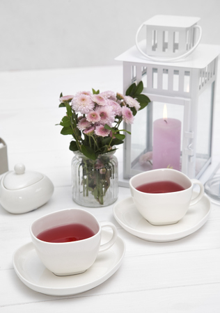 cups of fruit tea on wooden white table decorated with flowersの写真素材