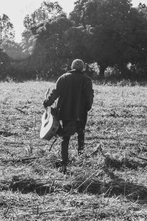 Old man with a guitar in the field. Black and white photo.の写真素材