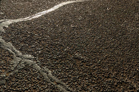 Asphalt road with cracks and scratches, detail of cracked asphalt backgroundの写真素材