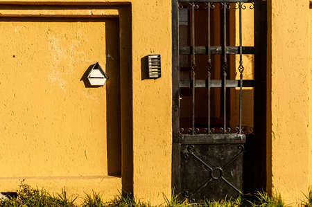 A closeup shot of a door in a yellow house with a metal latticeの写真素材