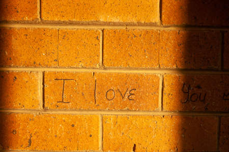 I love you written on a brick wall in a sunny day.の写真素材